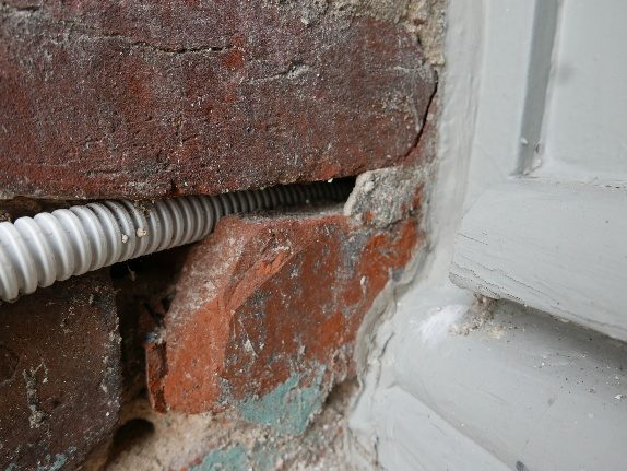 Unsauber ausgeführter Rohrdurchbruch im Mauerwerk